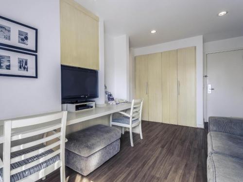 a living room with a desk with a tv and a couch at Mercure Sao Paulo Moema in Sao Paulo