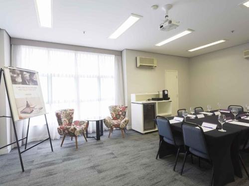 a conference room with a table and chairs and a podium at Mercure Sao Paulo Moema in Sao Paulo