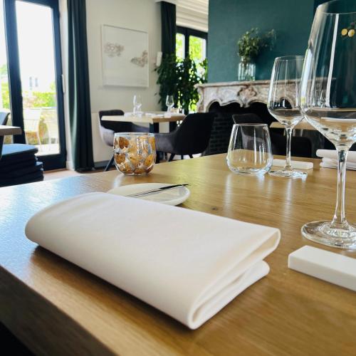 a wooden table with wine glasses and a white napkin at Charme logies Kampernoelie in Hoeselt