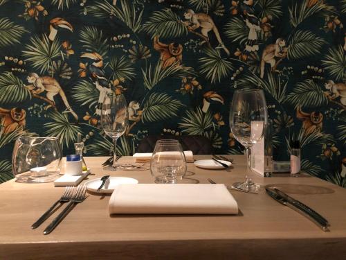 a table with glasses and napkins on a table with a wallpaper at Charme logies Kampernoelie in Hoeselt