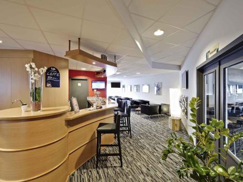 a lobby with a bar with chairs and a waiting room at ibis Brussels Waterloo in Waterloo