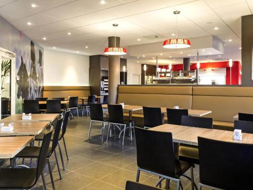 a dining room with wooden tables and chairs at ibis Brussels Waterloo in Waterloo
