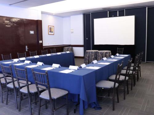 a conference room with blue tables and chairs and a screen at Novotel Monterrey Valle in Monterrey