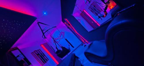 a room with purple and pink lights and a chair at L'escale du désir, Spa privatif in Calais