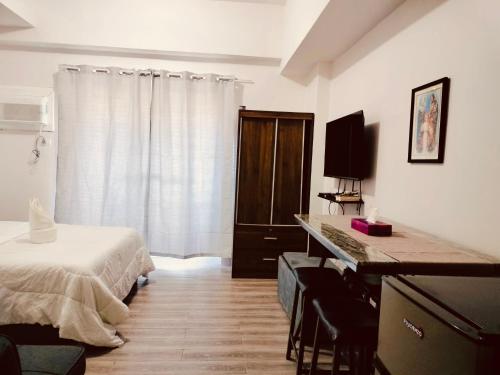 a bedroom with a bed and a desk with a television at Amani Grand Resort Residences near Mactan Cebu Intl Airport in Mactan