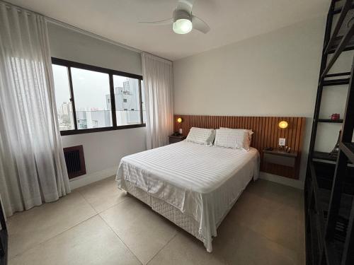 a bedroom with a white bed and a large window at ENB Flat Super Moderno com AC no Centro de SBC in São Bernardo do Campo