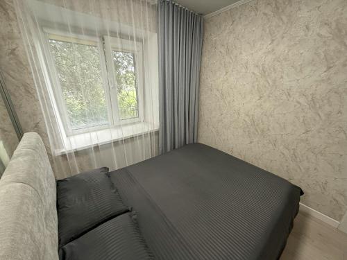 ein Schlafzimmer mit einer Couch und einem Fenster in der Unterkunft 1-комнатная квартира в центре на 1 Мая 81 in Qostanai