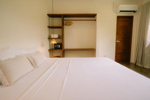 a large white bed in a room with a door at Ananda House in El Nido