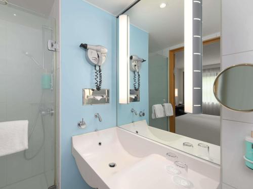 a bathroom with a tub and a sink and a mirror at Novotel Aachen City in Aachen