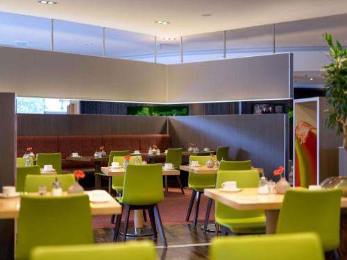 a dining room with tables and green chairs at Novotel Aachen City in Aachen