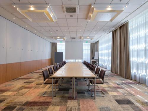 a long conference room with a long table and chairs at Novotel Aachen City in Aachen