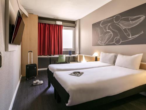 a hotel room with two beds and a desk at Ibis Madrid Getafe in Getafe