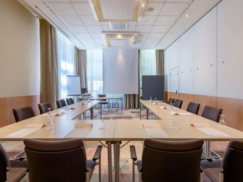 a conference room with long tables and chairs at Novotel Aachen City in Aachen