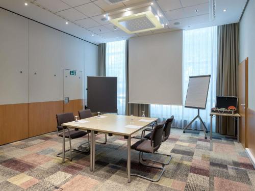 a conference room with a table and chairs and a whiteboard at Novotel Aachen City in Aachen
