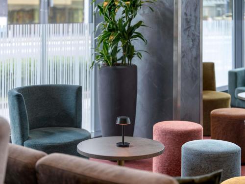 a lobby with chairs and a table and a potted plant at Novotel Aachen City in Aachen