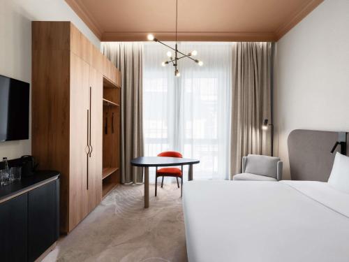 a bedroom with a bed and a table and a chair at Mövenpick Hotel Budapest Centre in Budapest