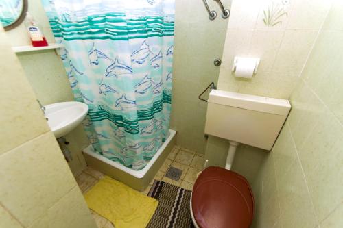 a bathroom with a toilet and a shower curtain at Sobe Andreis in Vela Luka