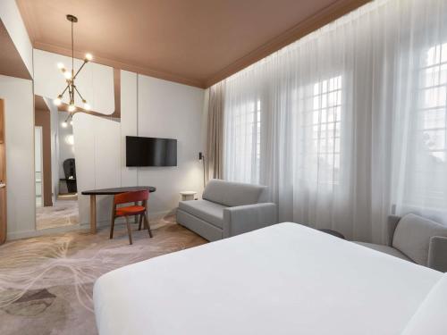 a hotel room with a bed and a chair and a table at Mövenpick Hotel Budapest Centre in Budapest