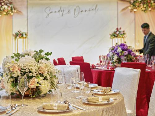 a table with flowers and a man in the background at Novotel Century Hong Kong in Hong Kong