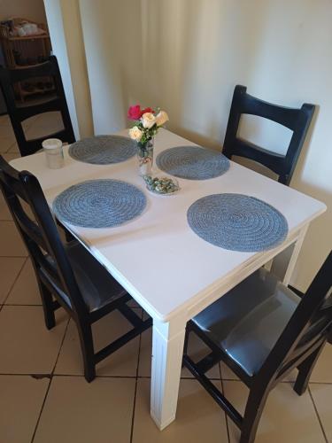 une table blanche avec quatre chaises et un vase avec des fleurs dans l'établissement Pebs one bedroom apartment, à Mombasa