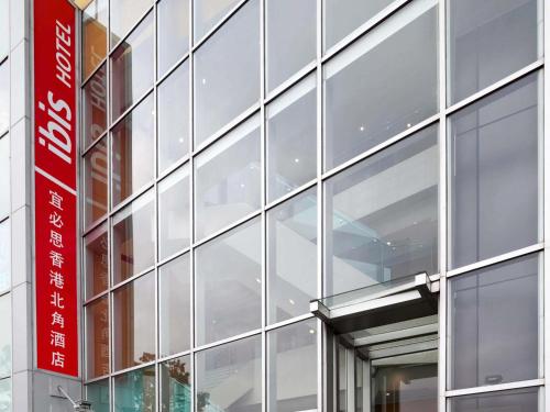 a glass facade of a building with a red sign at ibis Hong Kong North Point in Hong Kong