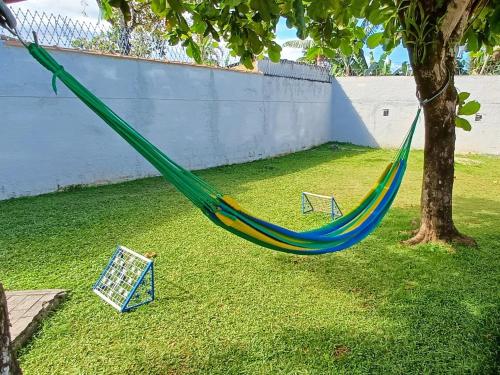 una hamaca colgada de un árbol en un patio en Casa Temporada Ubatuba próxima à praia, check-in e out flexíveis com 5 vagas na garagem, wifi, en Ubatuba