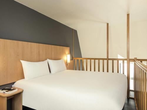 a bedroom with a large white bed and a staircase at ibis Paris Bastille Faubourg St Antoine in Paris