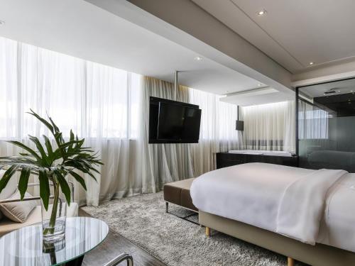 a hotel room with a bed and a tv at Mercure Belo Horizonte Lourdes in Belo Horizonte