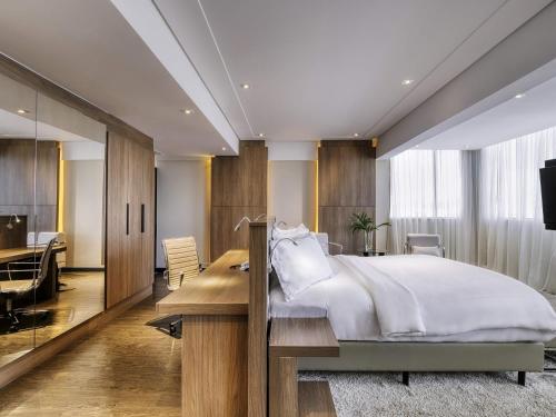 a bedroom with a large bed and a desk and a desk at Mercure Belo Horizonte Lourdes in Belo Horizonte
