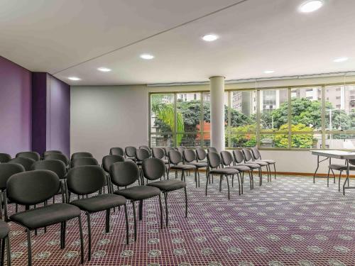 a conference room with chairs and tables and windows at Mercure Belo Horizonte Lourdes in Belo Horizonte