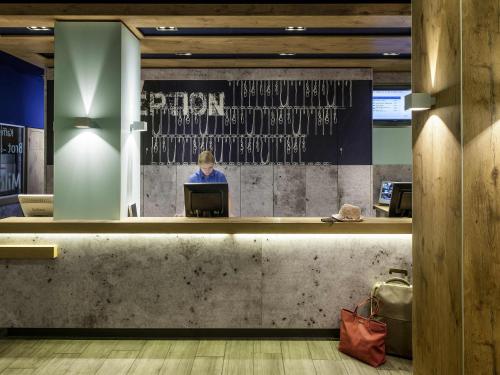 a person sitting at a computer in a lobby at ibis Budget Luxembourg Aeroport in Luxembourg