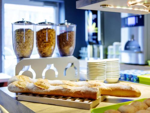 a loaf of bread sitting on a counter with three glasses at ibis Budget Luxembourg Aeroport in Luxembourg