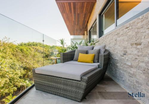 ein Korbstuhl mit einem gelben Kissen auf einem Balkon in der Unterkunft Condos with Private Jacuzzi and shared Ocean View Roof pool in Playa del Carmen