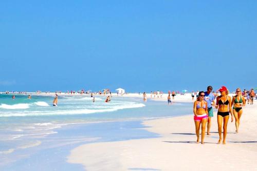 a group of people walking on the beach at Entire Siesta Key Beach House - 6 BR, Pool & Ocean Access in Siesta Key