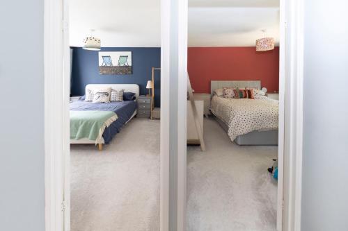 a bedroom with two beds and red walls at Haywards Heath 2BR House w Parking in Lindfield