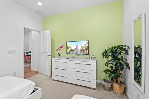 a bedroom with a white dresser with a tv on it at Family 4BR Private Pool BBQ Resort Stay in Kissimmee