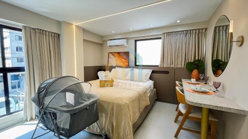 une chambre d'hôtel avec un lit et une table avec une poussette dans l'établissement Bauten Áurea Cabo Branco Genius Flats, à João Pessoa