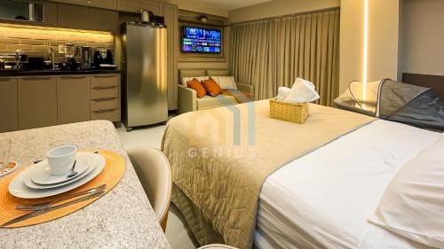 a hotel room with a bed and a table and a kitchen at Áurea Bauten Cabo Branco Genius Flats in João Pessoa