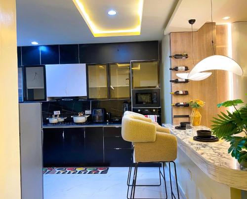 a kitchen with black cabinets and a yellow chair at Lagos StayHub in Lagos
