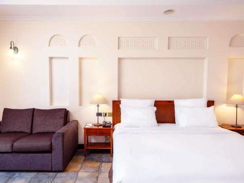 a hotel room with a bed and a couch at Novotel Bahrain Al Dana Resort in Manama