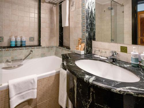 a bathroom with a sink and a bath tub at Novotel Bahrain Al Dana Resort in Manama