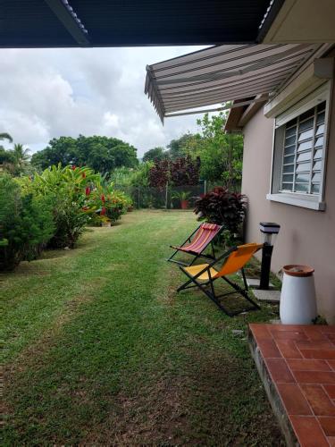 two chairs sitting in the yard of a house at TI-KAZ fleurie, l'escapade bouillonaise in LʼAjoupa-Bouillon