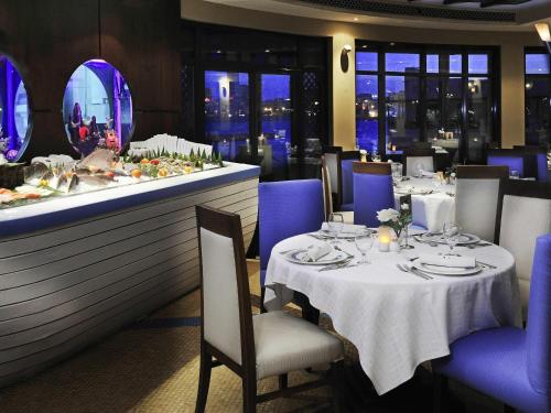 a restaurant with tables and chairs and a counter at Novotel Bahrain Al Dana Resort in Manama