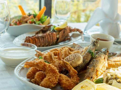 a table with two plates of seafood and other foods at Novotel Bahrain Al Dana Resort in Manama