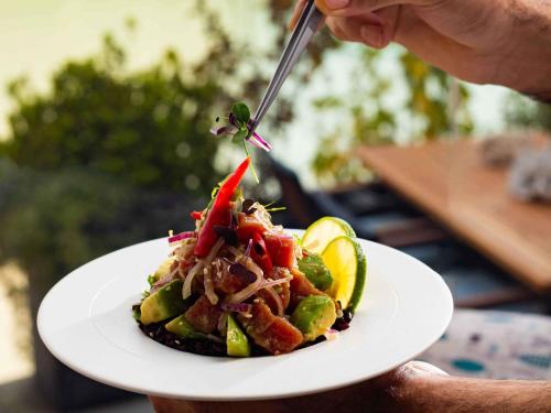 a person holding a plate of food with a fork at Novotel Bahrain Al Dana Resort in Manama