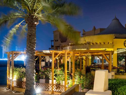 a hotel with a palm tree in front of a building at Novotel Bahrain Al Dana Resort in Manama