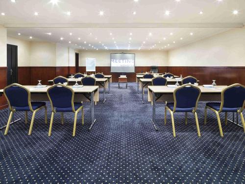 a conference room with tables and chairs and a screen at Novotel Bahrain Al Dana Resort in Manama