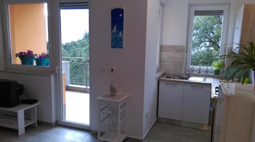 a kitchen with white cabinets and a balcony with windows at Apartment Julie 4 in Rijeka