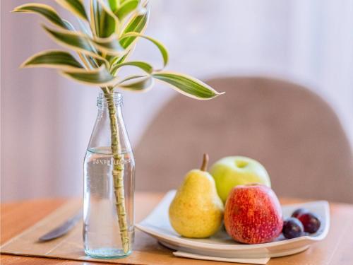 Un jarrón de agua y un plato de fruta sobre una mesa. en Grand Mercure Brasilia Eixo Monumental, en Brasilia