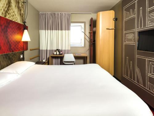 a hotel room with a large bed and a desk at ibis London Excel-Docklands in London